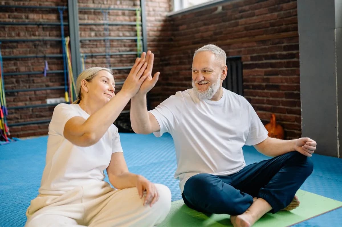 Older couple on exercise mats smiling and giving each other a high five