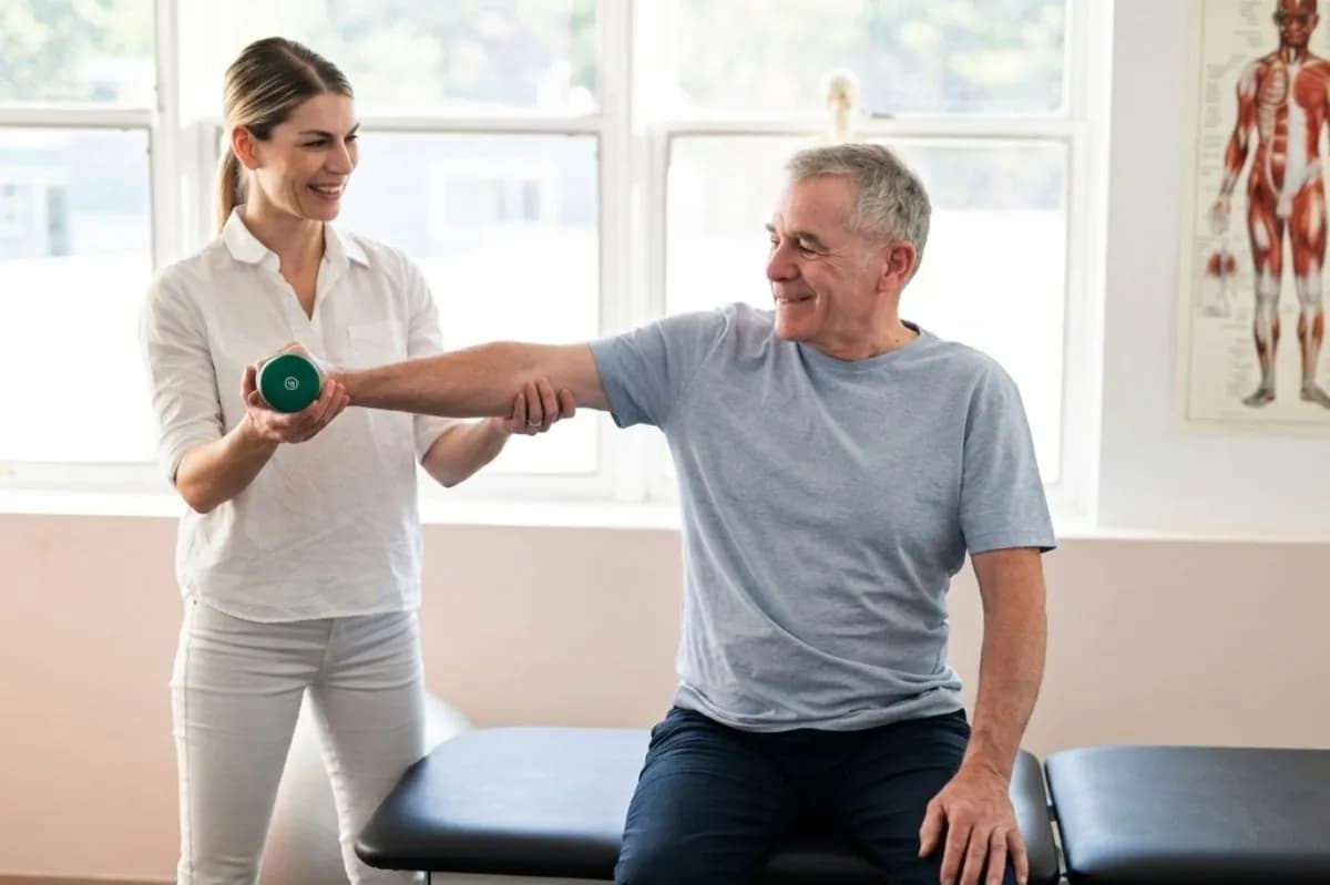 Physiotherapist guiding an older man through an arm exercise with a small weight