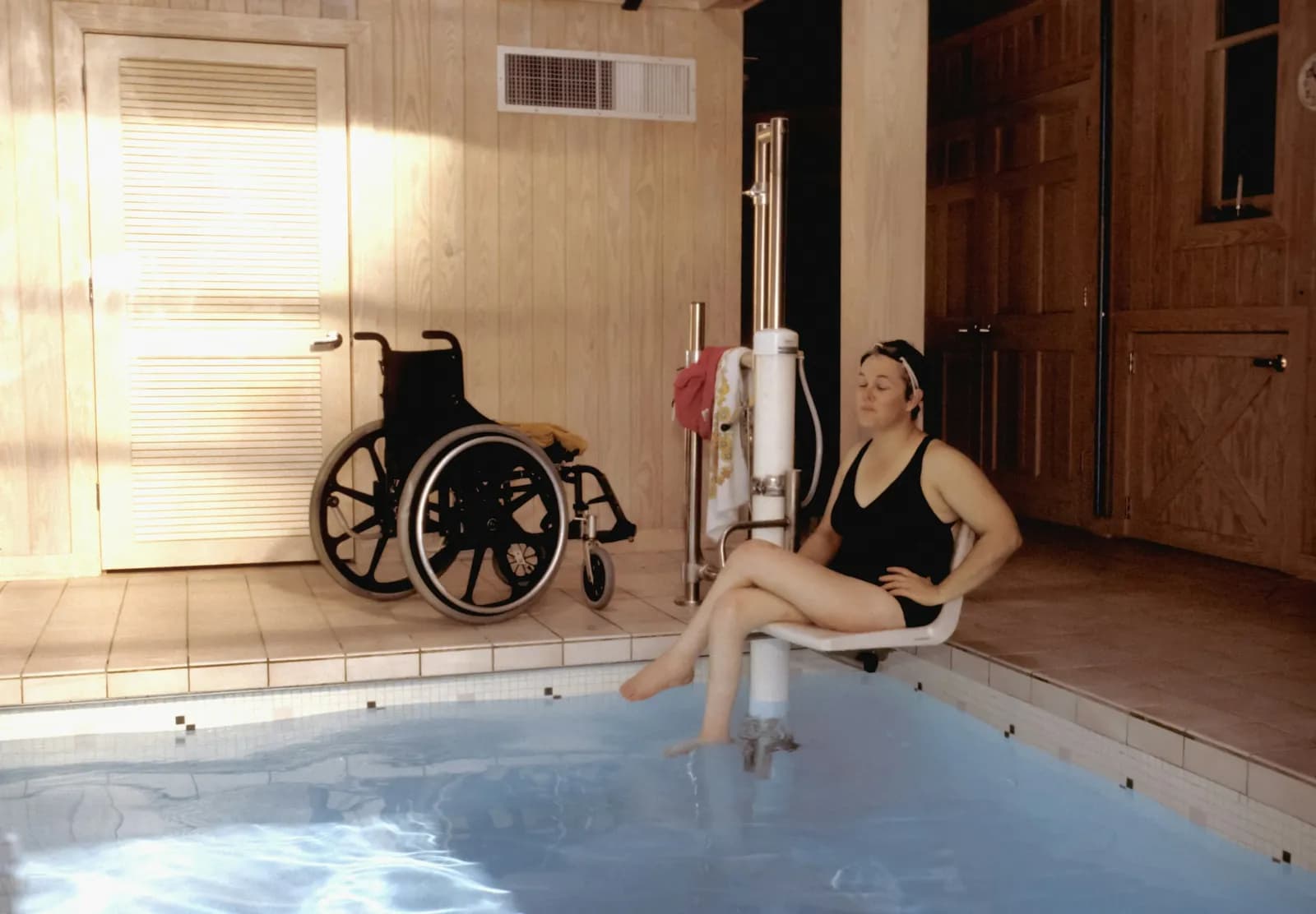Woman seated at the edge of a warm indoor therapy pool