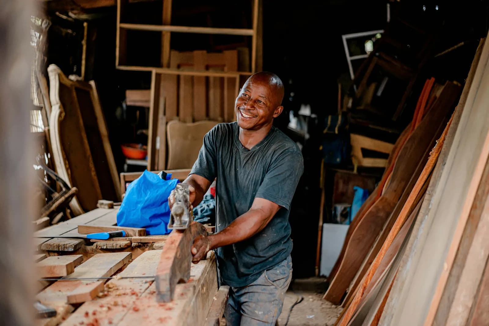 Carpenter smiling as he works with timber in his workshop
