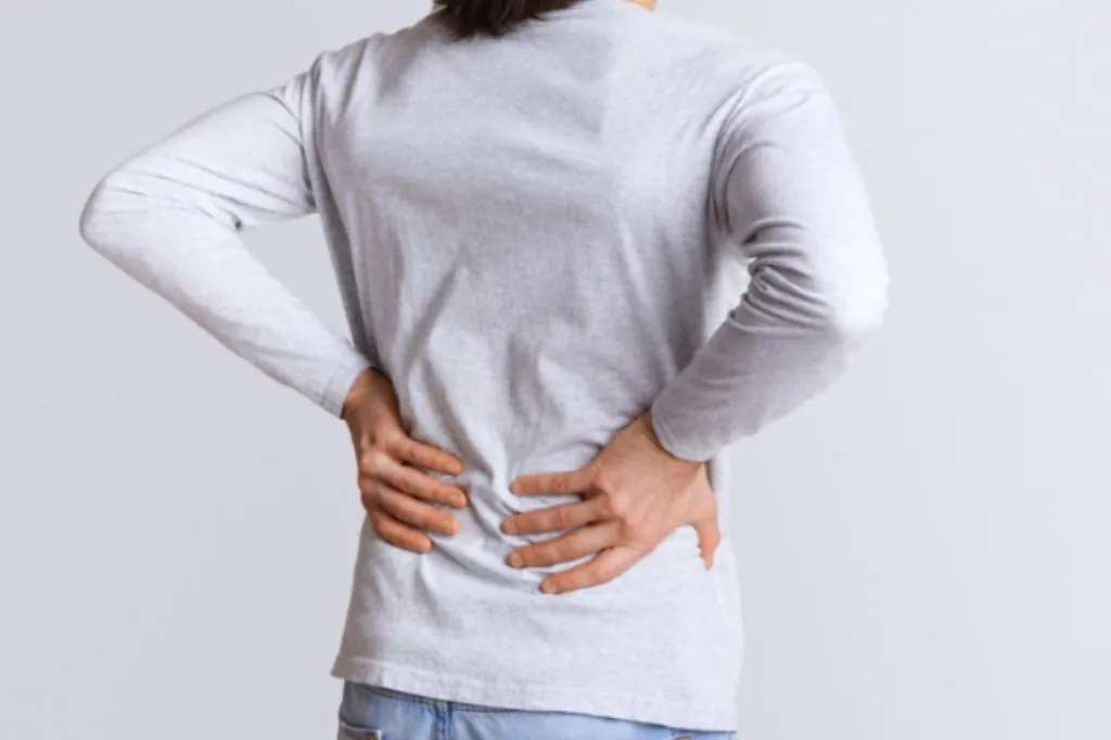 Person in a grey top holding their lower back