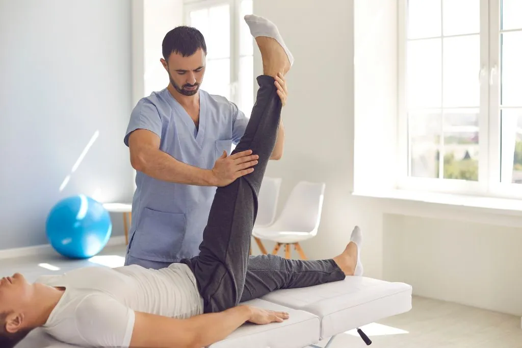 Physiotherapist stretching a patient's leg on a treatment table