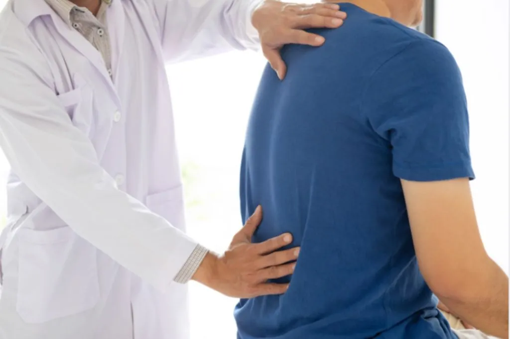 Clinician placing his hands on a man's lower back during an assessment